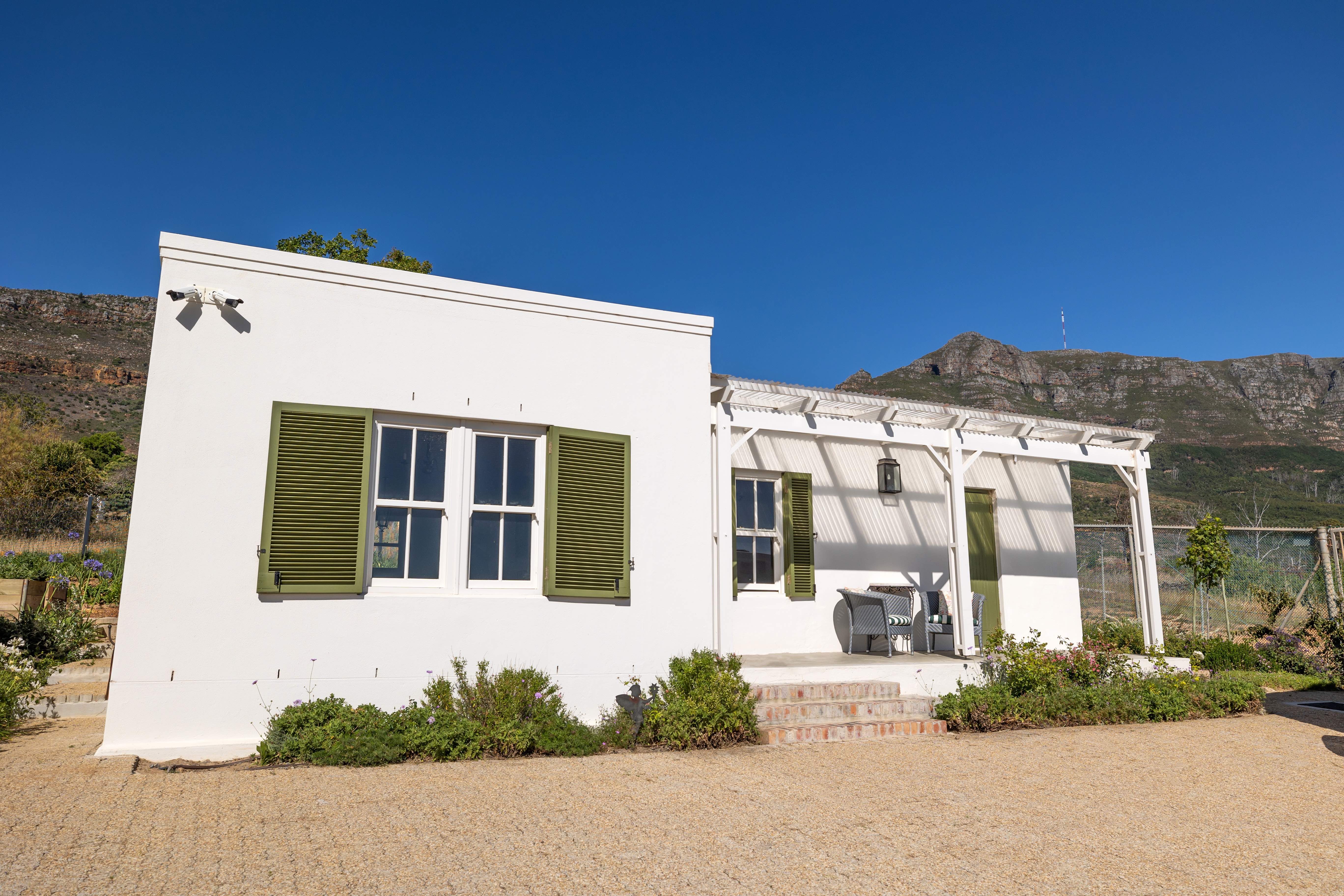 White cottage with green shutters and mountain backdrop