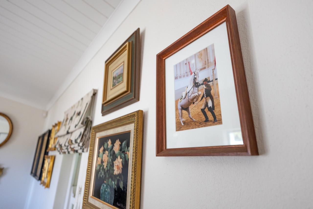 Gallery wall showing framed equestrian artwork and paintings in tea room
