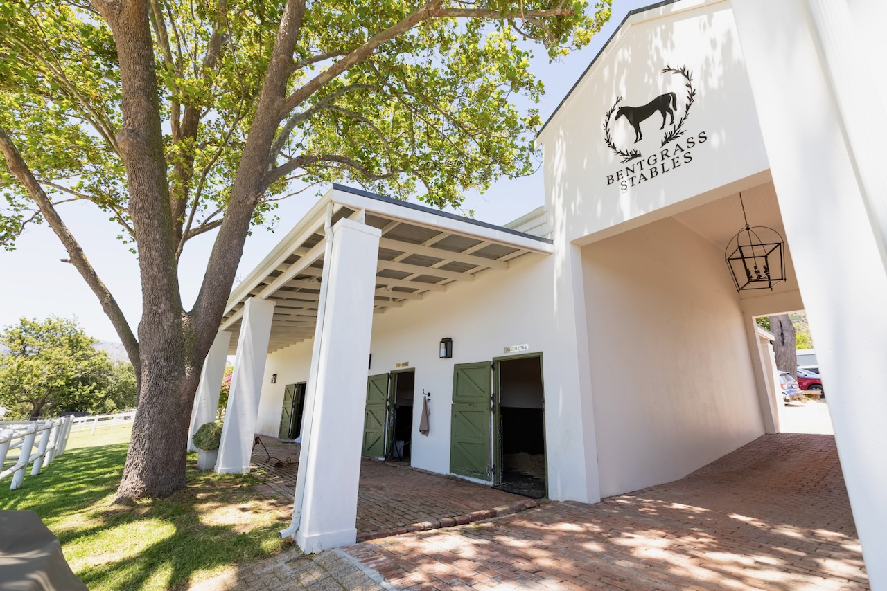 Exterior view of main stable building with Bentgrass Stables logo and white columns