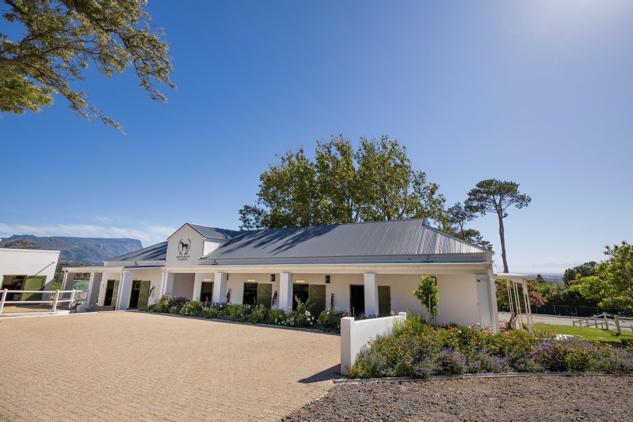 Full length exterior view of stable building with mountain views and landscaping